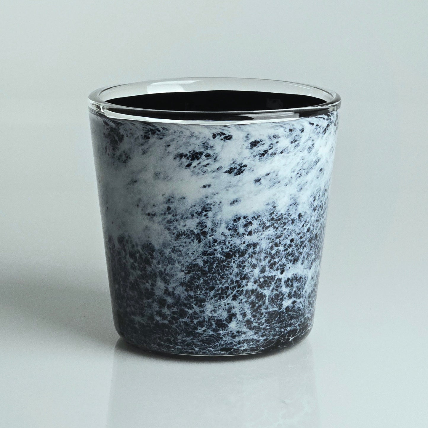 A small clear glass planter with a black rim, featuring a marbled black and white pattern on the lower half and a solid black interior, set against a light gray background.