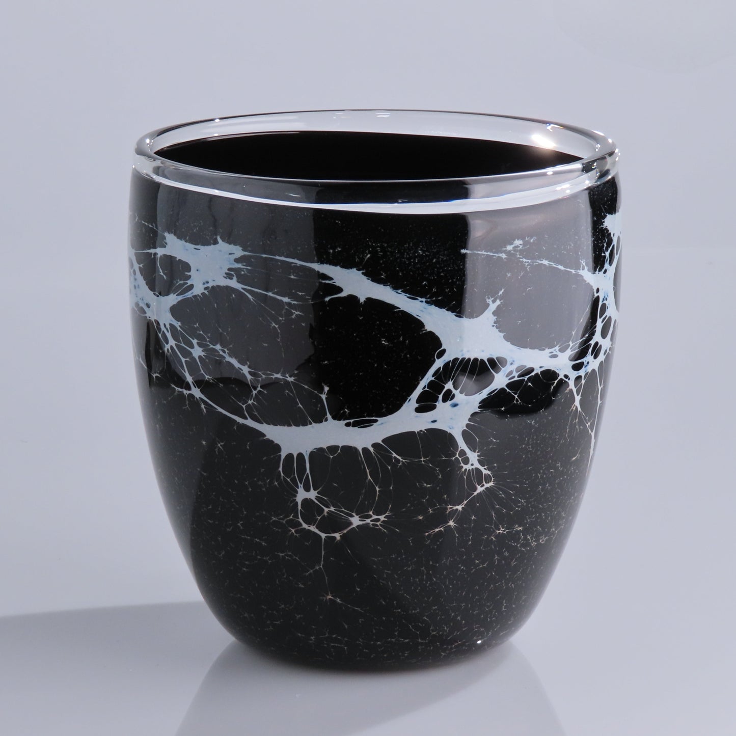 A glossy black glass planter with a white marble vein pattern, photographed on a light gray background.