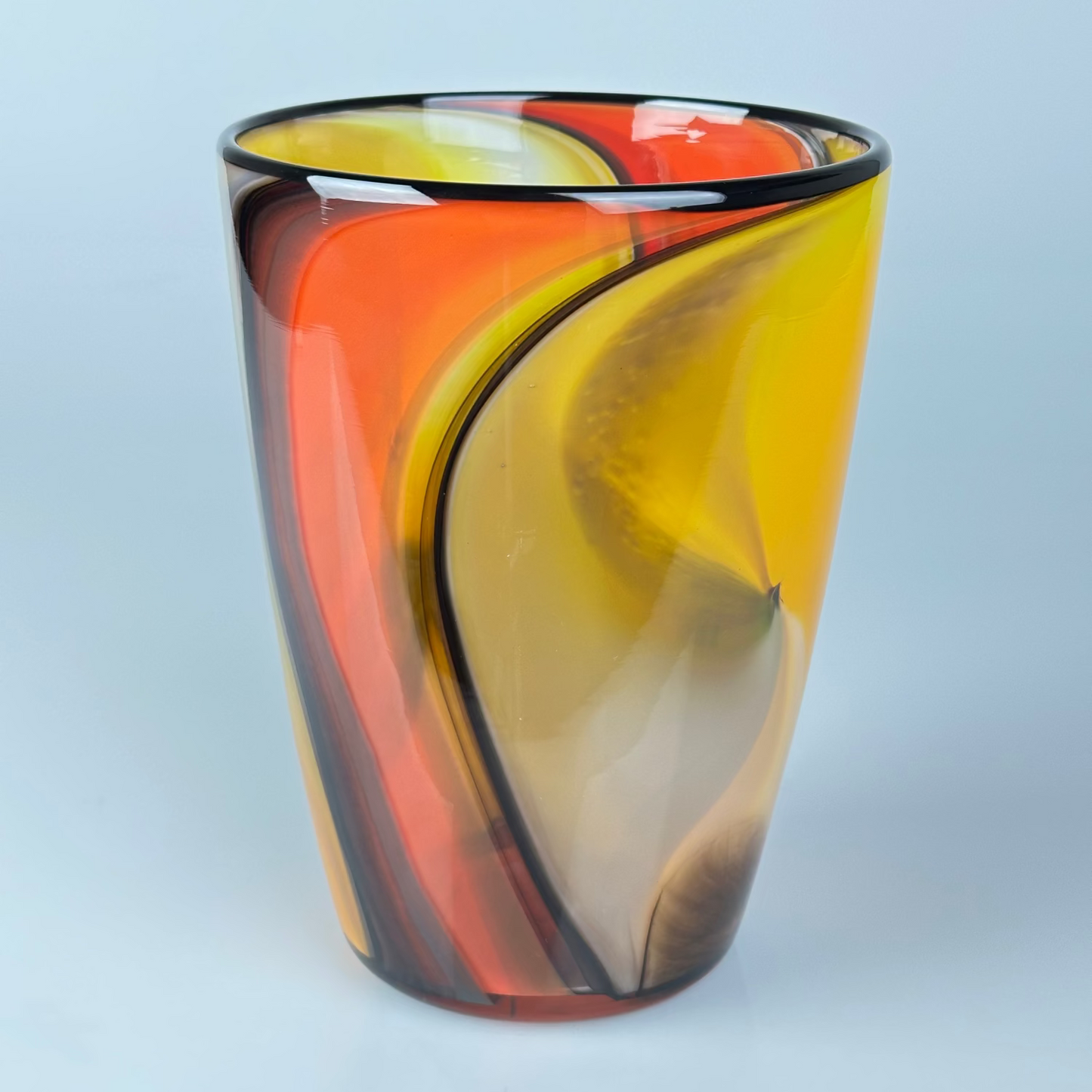 A hand-blown glass vase with a modern organic swirl pattern in vibrant yellow, orange, red, and brown tones.